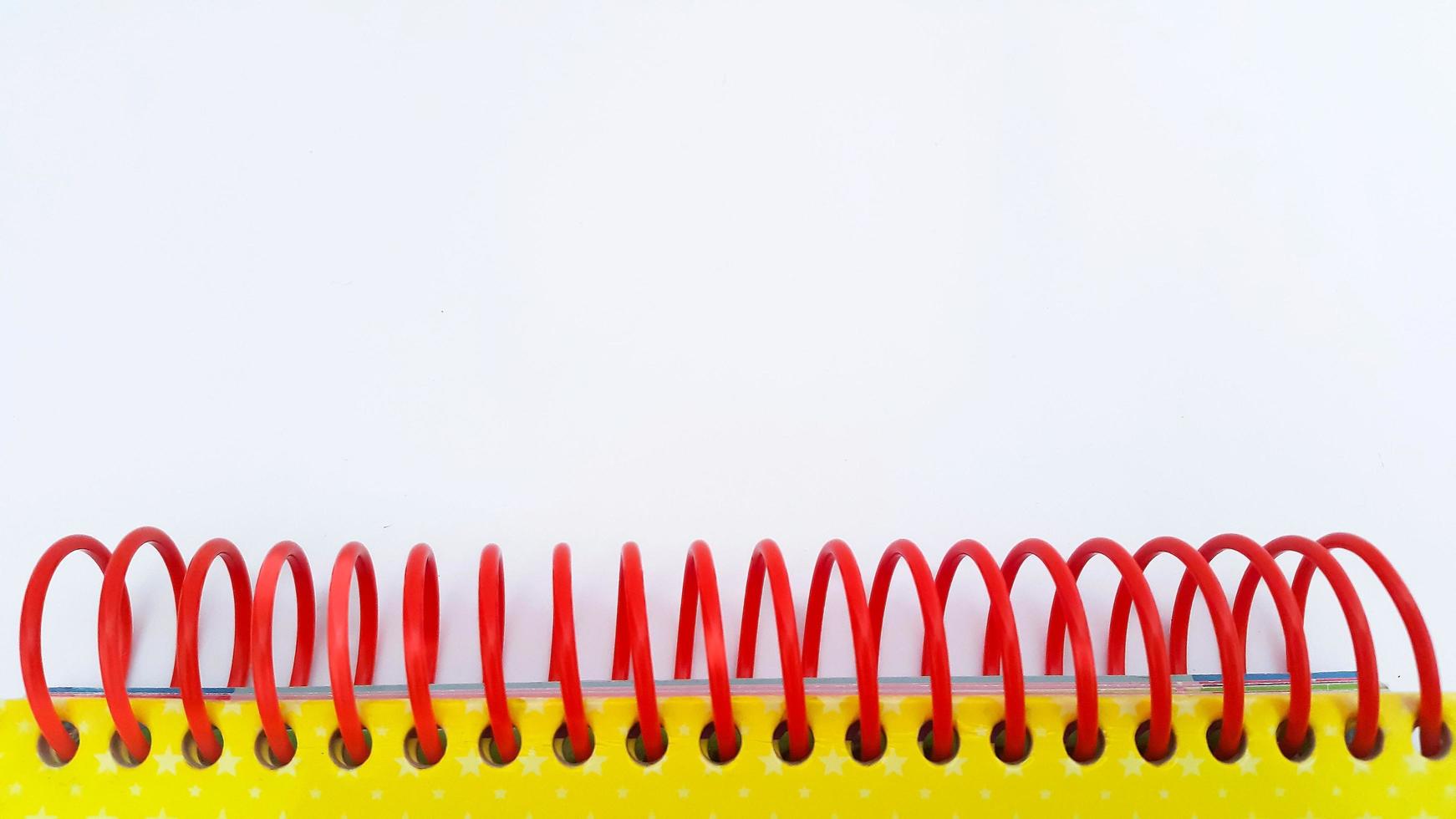 Close-up of red spiral bound notebook on white background photo