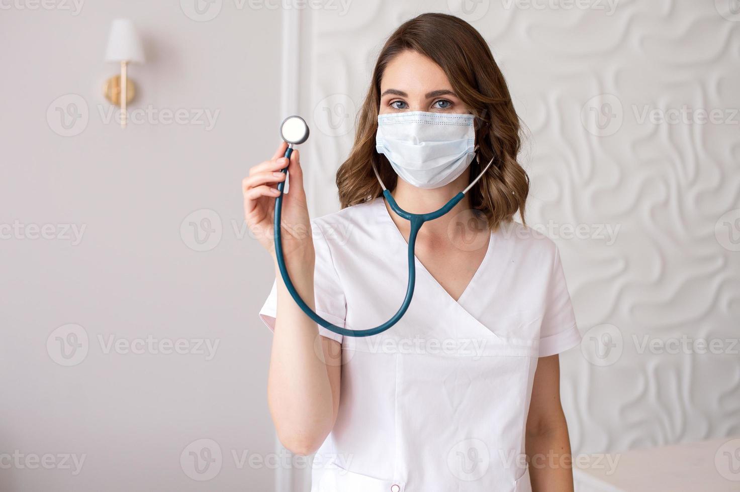 Cute girl doctor in a medical mask shows a stethoscope photo