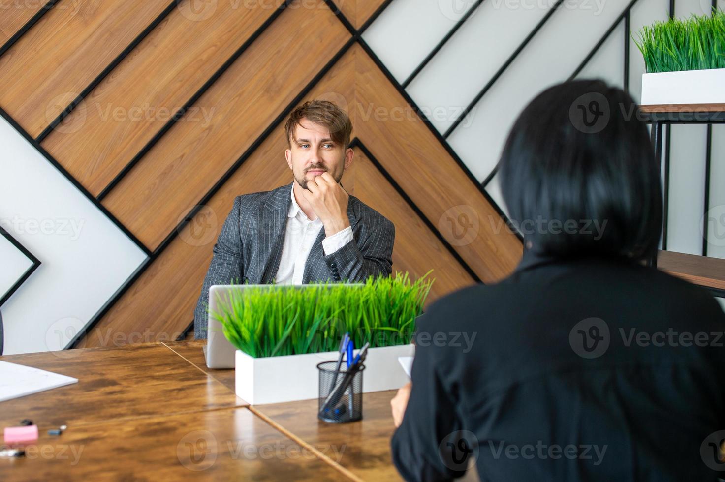 A man in a suit is sitting with a laptop and negotiating photo