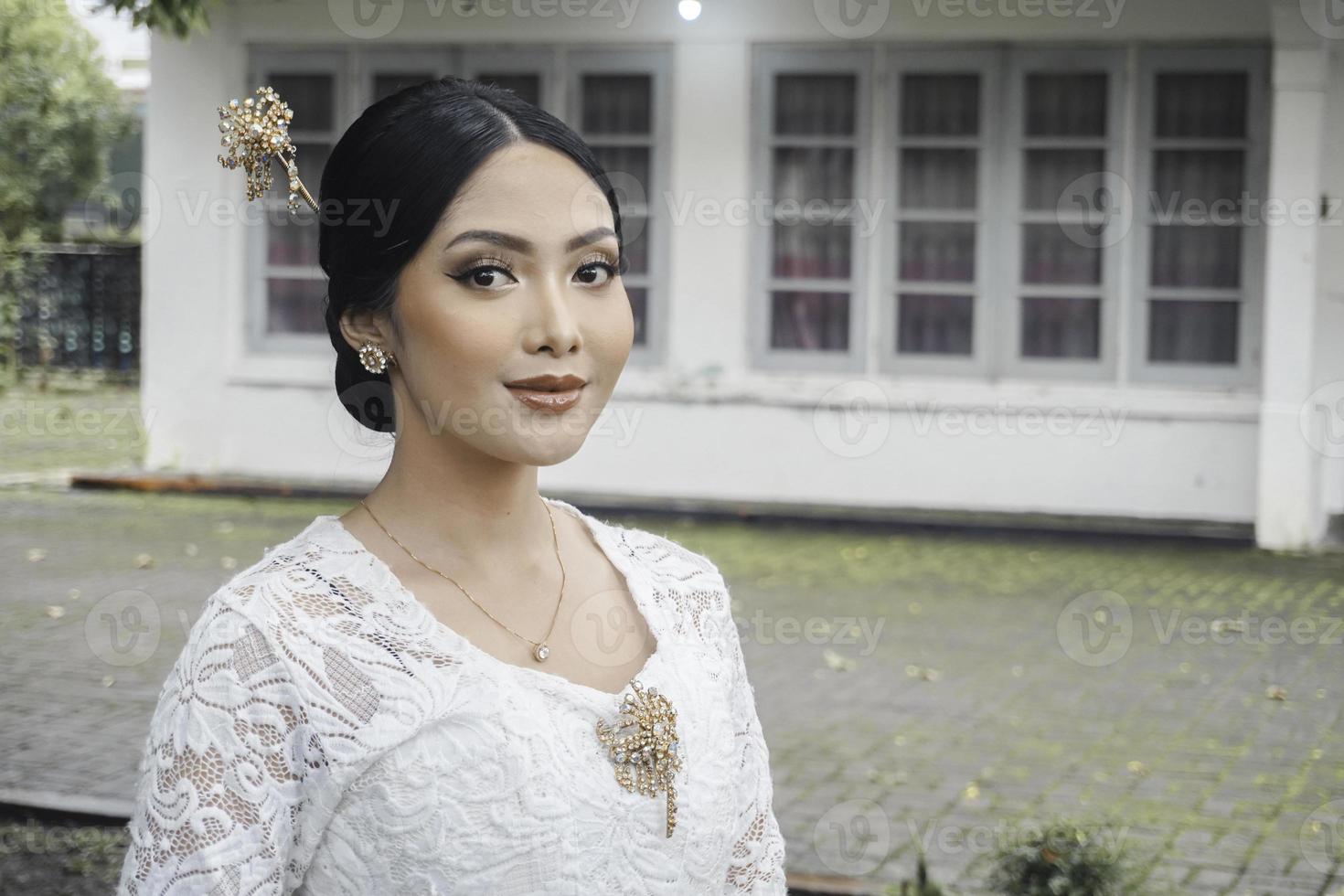 A young Indonesian woman with a happy successful expression wearing a white kebaya. Kartini's Day Concept. photo