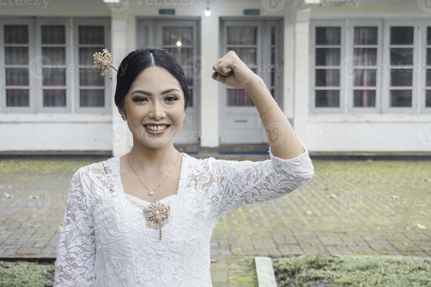 A young Indonesian woman with a happy successful expression wearing a white kebaya. Kartini's Day Concept. photo