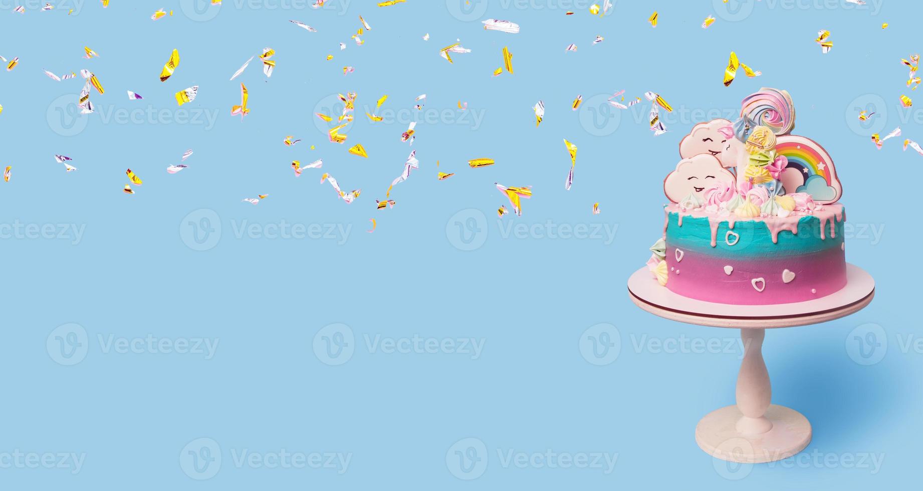 Beautiful festive children's cake with a unicorn on a stand on a blue background with falling golden confetti banner format photo