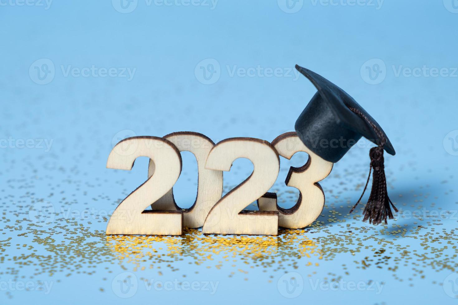 Class of 2023 concept. Wooden number 2023 with graduated cap on colored background photo