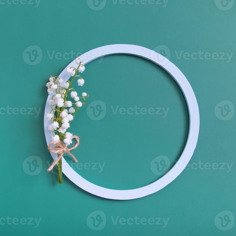 Summer or spring composition. Lily of the valley flowers with round frame copy space top view. Summer, spring floral concept photo