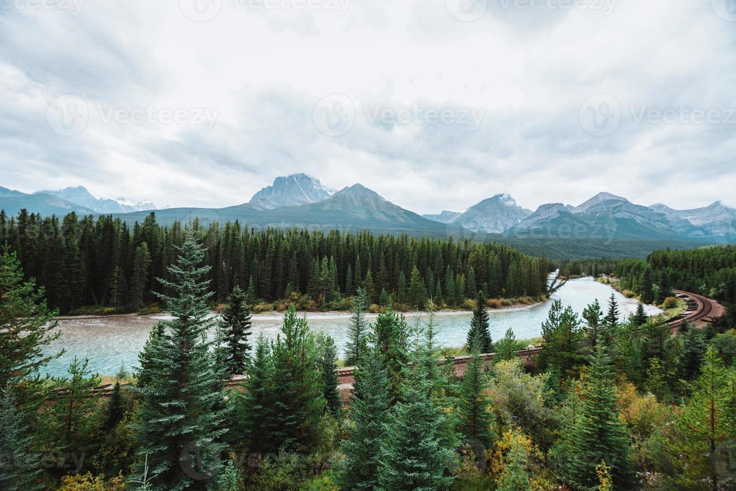 Morant's Curve, Bow River flows through forest and railway track. Storm Mountain in the background. Castle Cliff Viewpoint, Bow Valley Parkway, Banff National Park, Canadian Rockies, Alberta, Canada. photo