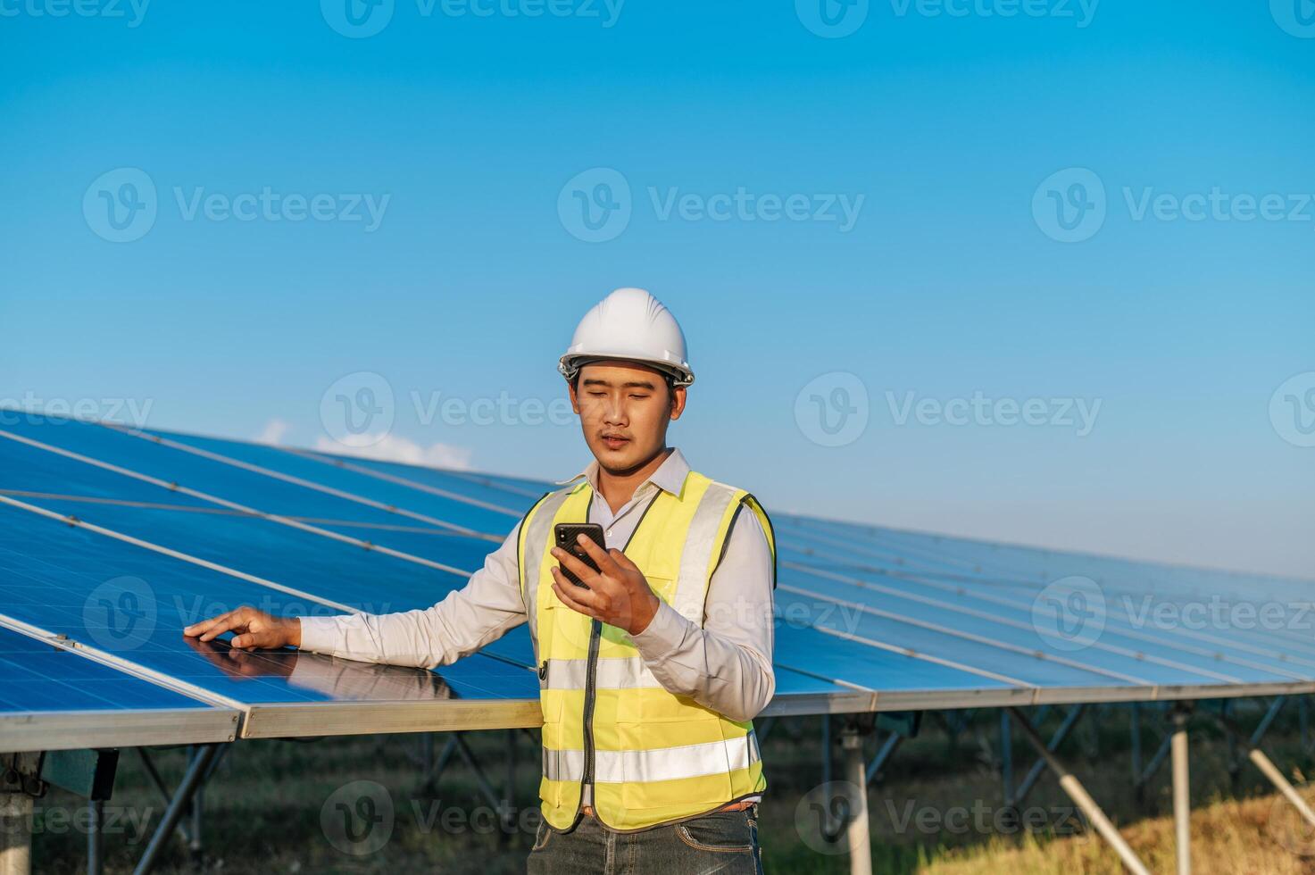 joven ingeniero usa un teléfono inteligente mientras trabaja en una granja solar foto