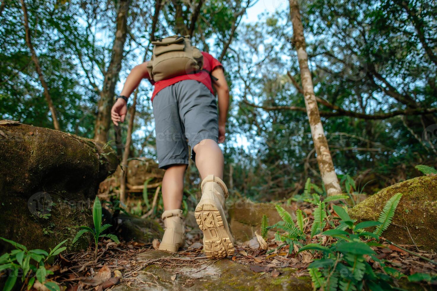 back of young trekking man with backpack walking up steep slope photo