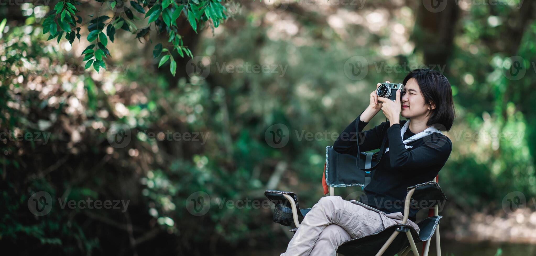 una mujer bonita joven usa una cámara para tomar fotos en un parque natural