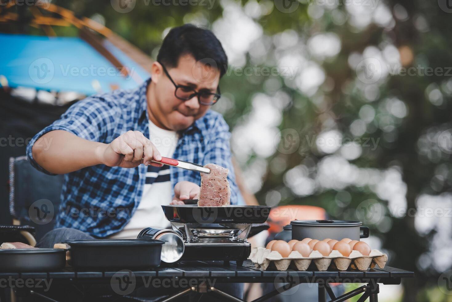 Portrait of Asian traveler man glasses pork steak frying photo