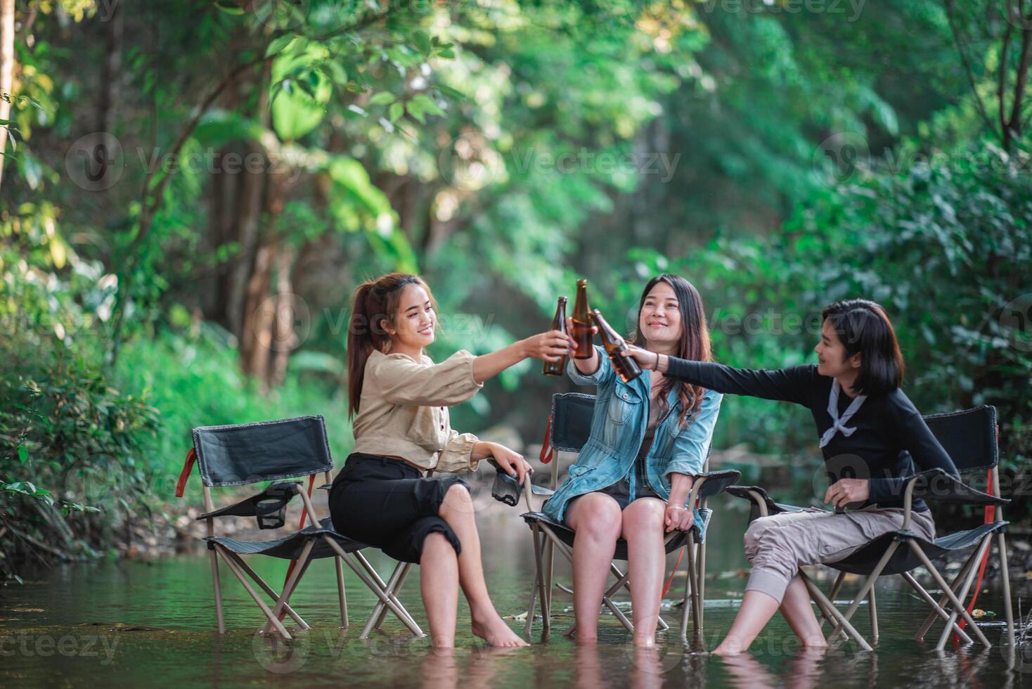 Young women sitting and drink beverage  while camping in forest photo