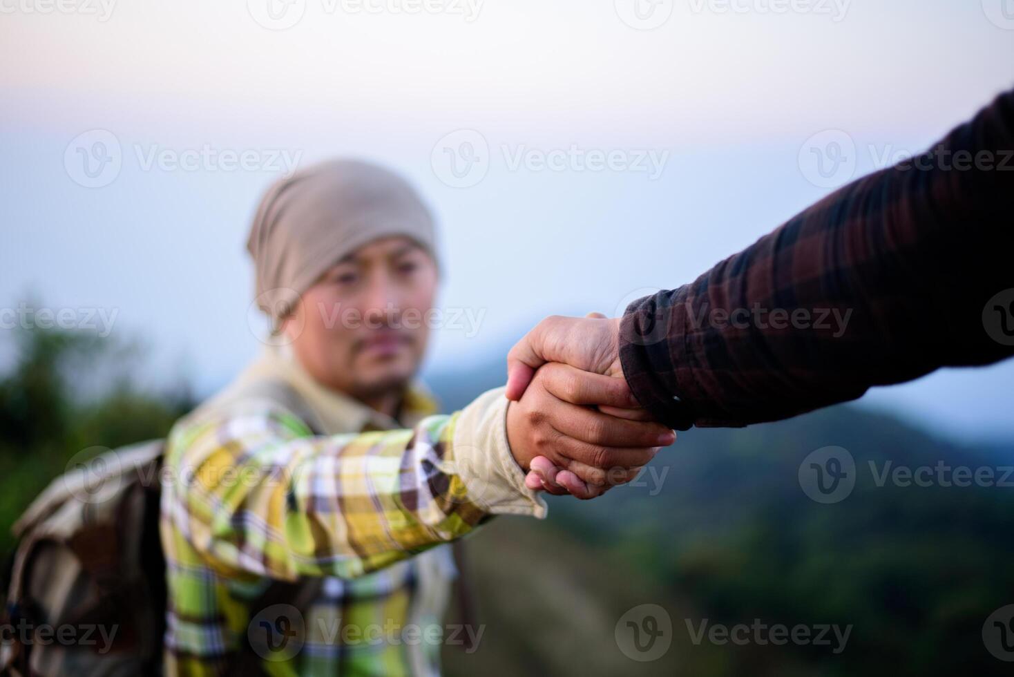 Close-up of Two male hikers helping each other climb up a mountain photo