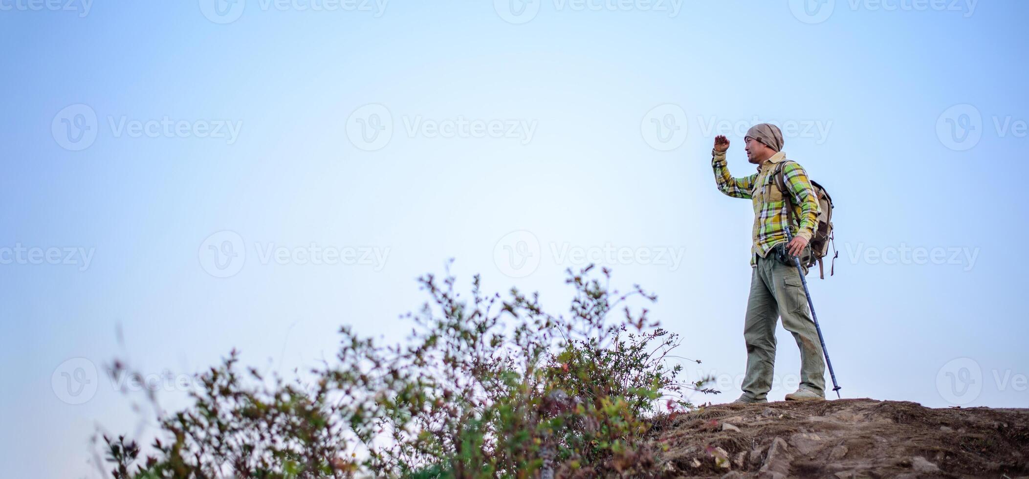 Hiker man standing on top of mountain or cliff and looking on valley photo