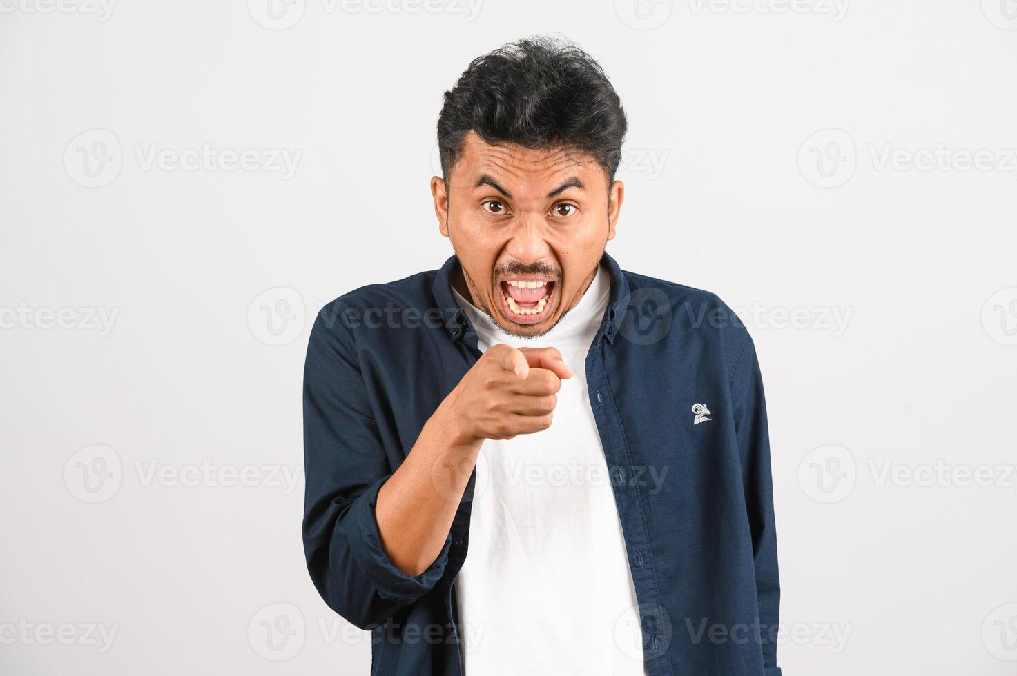 Portrait of Young asian man in blue shirt pointing towards the camera isolated on white background photo