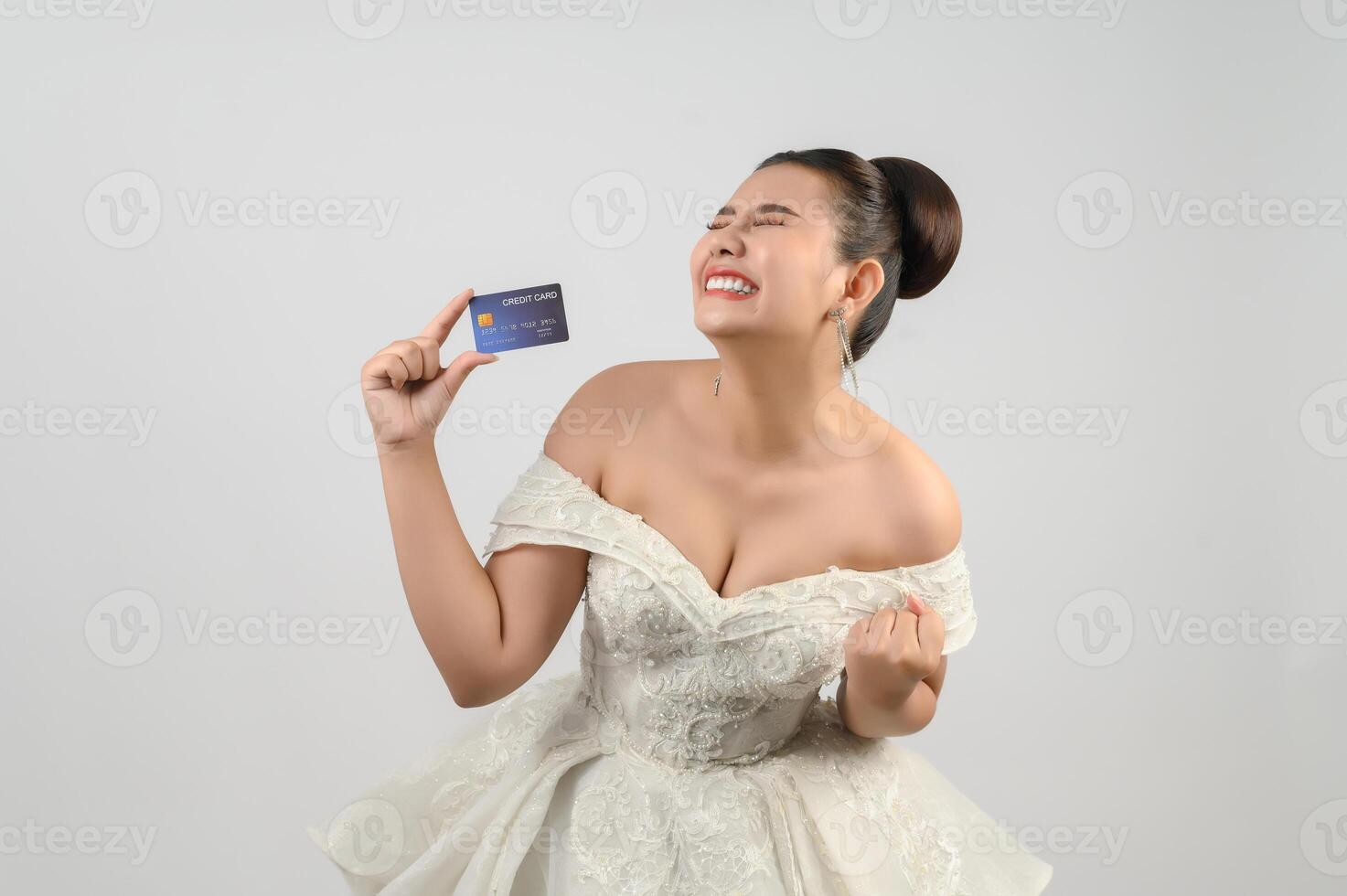 Young asian beautiful bride posting with credit card in hand photo