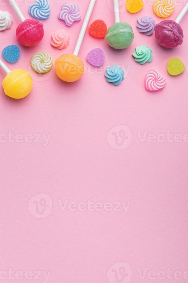 Sweet lollipops and candies on pink background photo