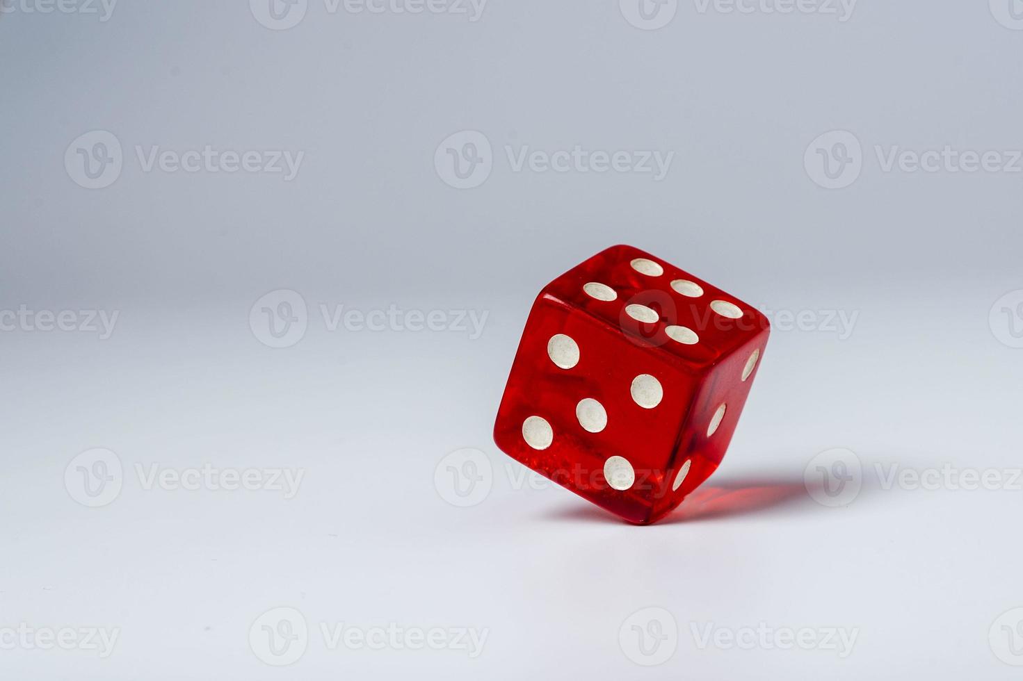 Red dice standing in equilibrium on the edge and showing 6 on a white table, red hexagonal cube standing in equilibrium photo