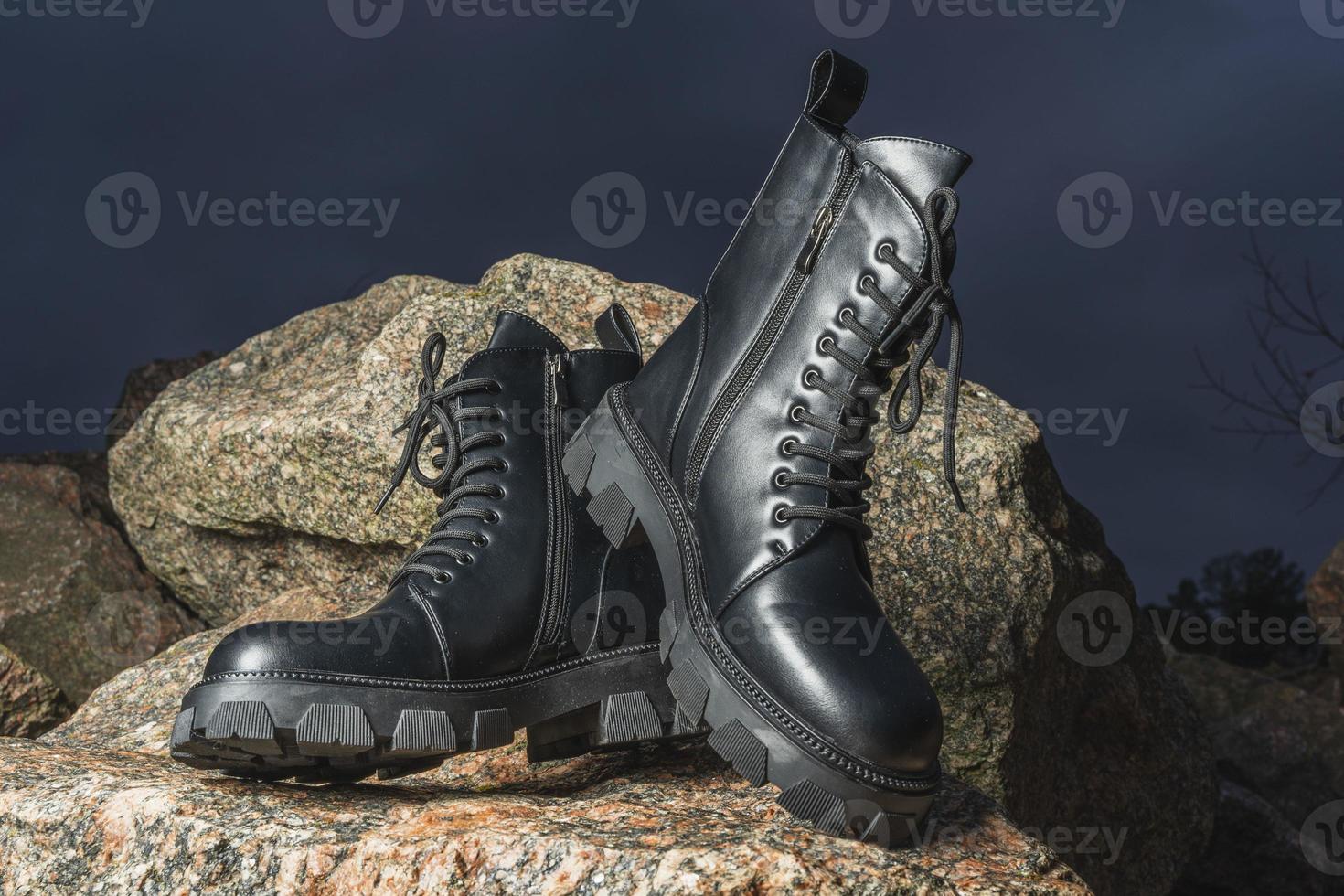 Leather black women's rough boots with thick soles on a background of stones photo