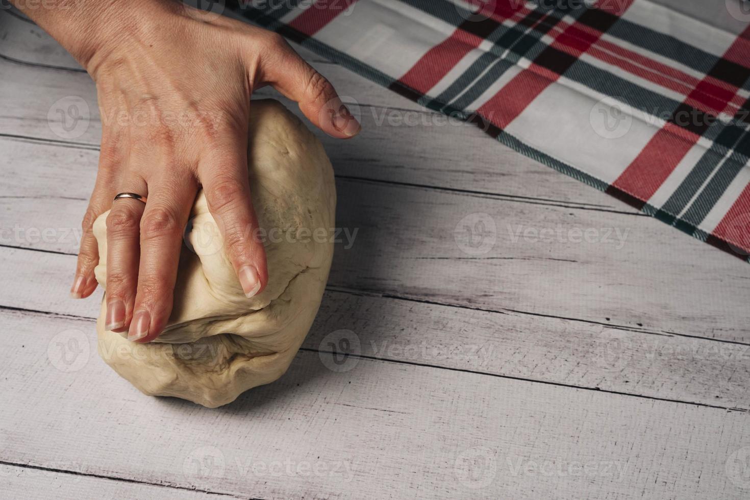 The chef's hands prepare and knead fresh homemade pizza dough on the kitchen table photo
