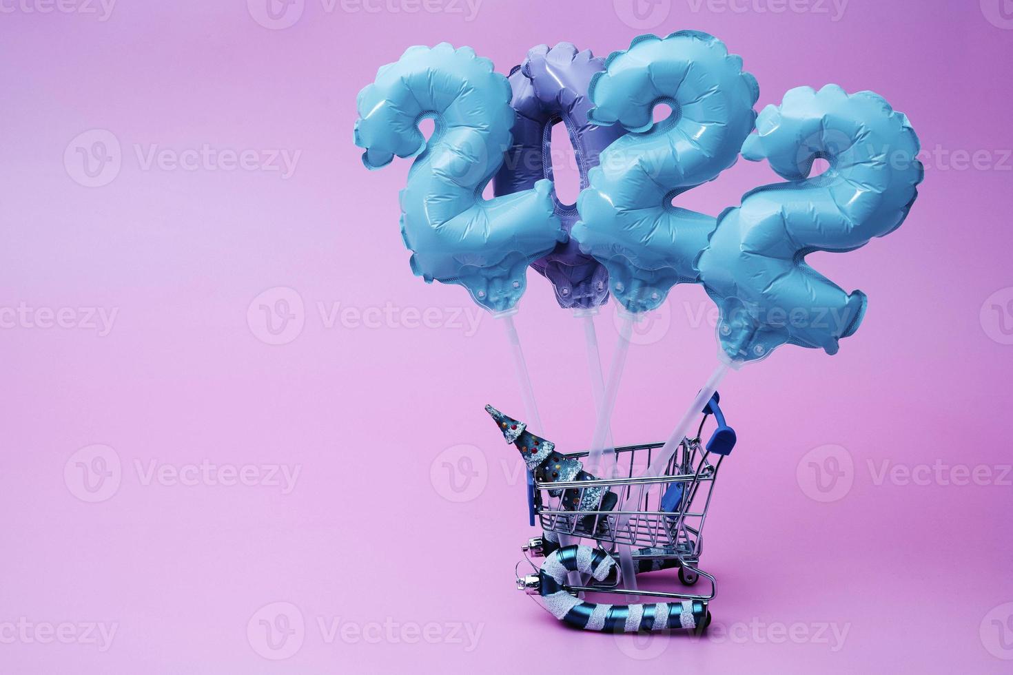 a cart from the supermarket carries inflatable figures with numbers 2022 year photo