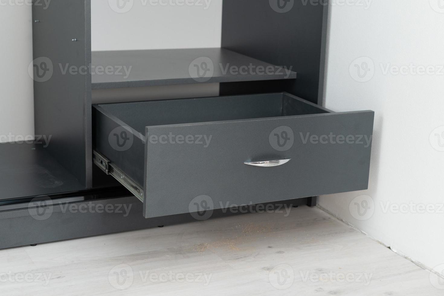Gray drawer in the middle of the cabinet, installation of cabinets in the house. photo