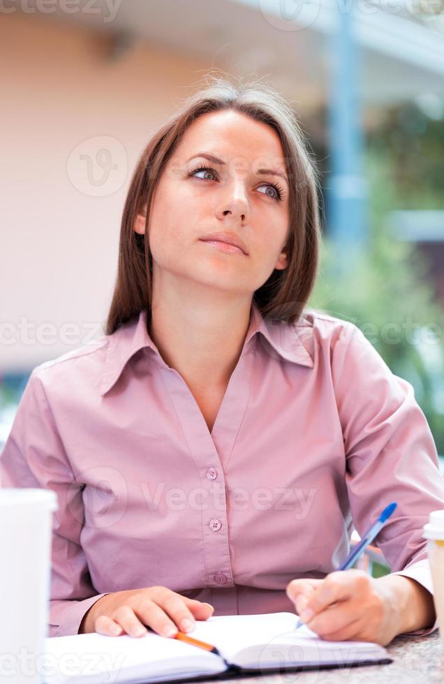 Businesswoman sitting in a cafe and writing in notepad photo