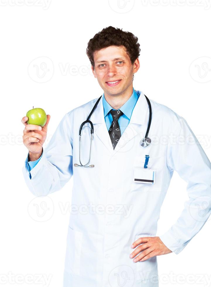 retrato de un sonriente masculino médico participación verde manzana en blanco foto