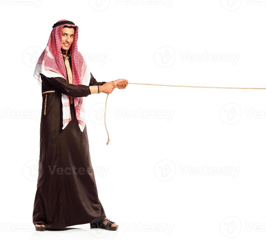 Young Arab pulling a rope isolated on white photo