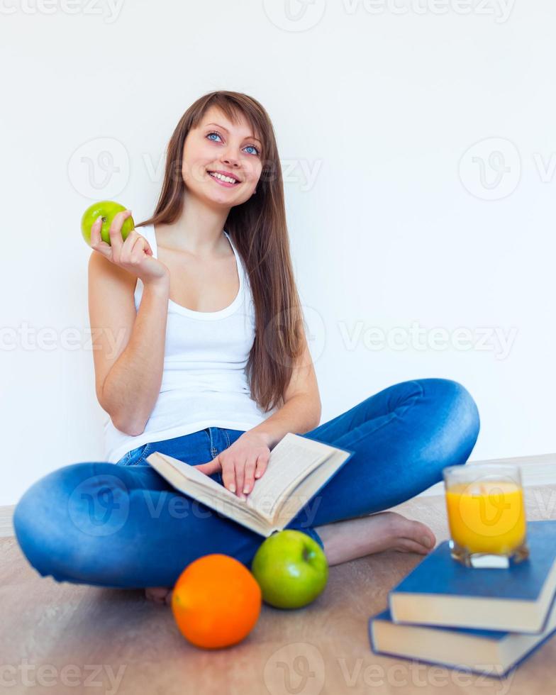 joven caucásico morena con manzana leyendo un libro foto