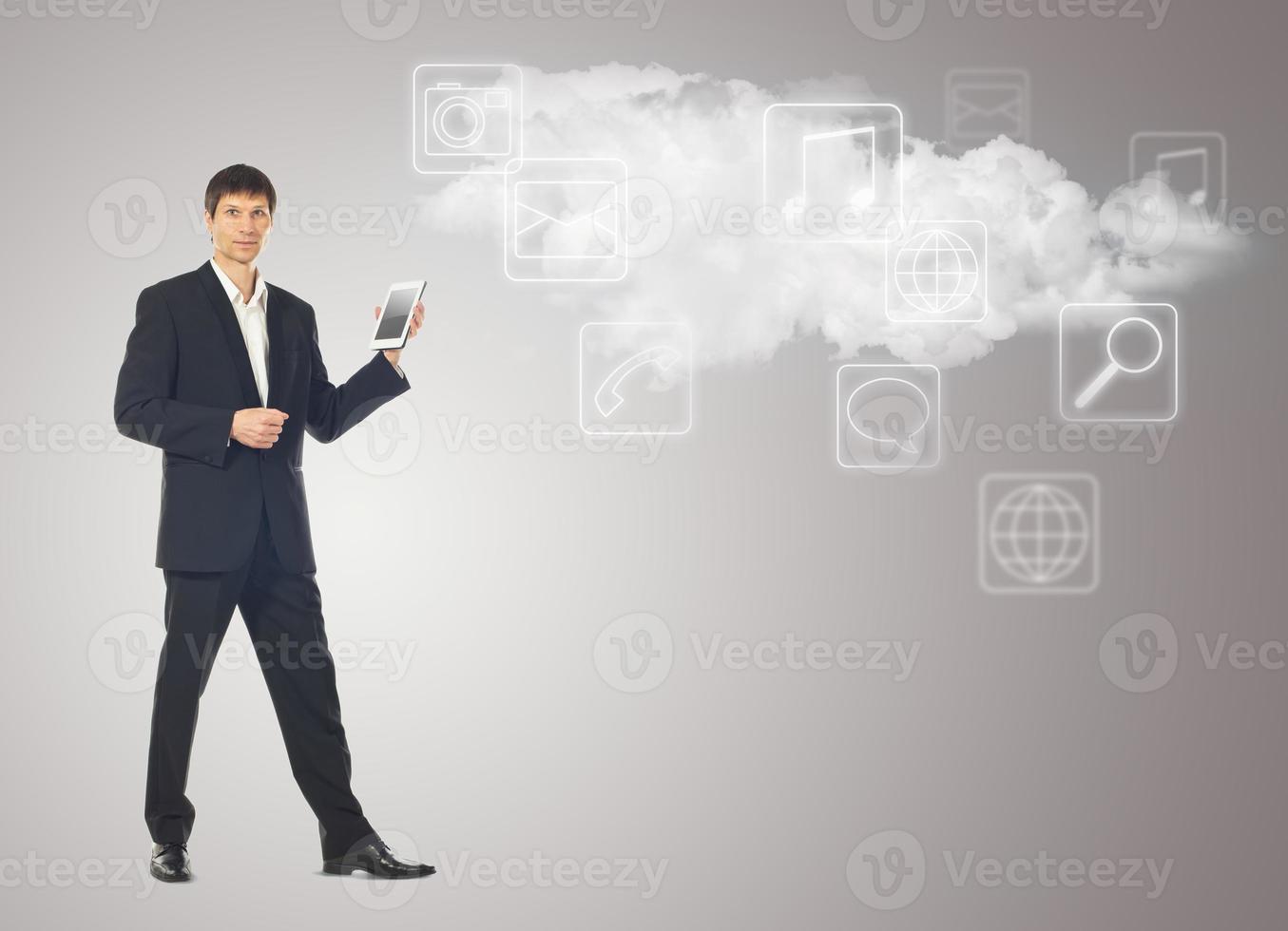 Businessman with tablet and the cloud with applications icons on grey photo