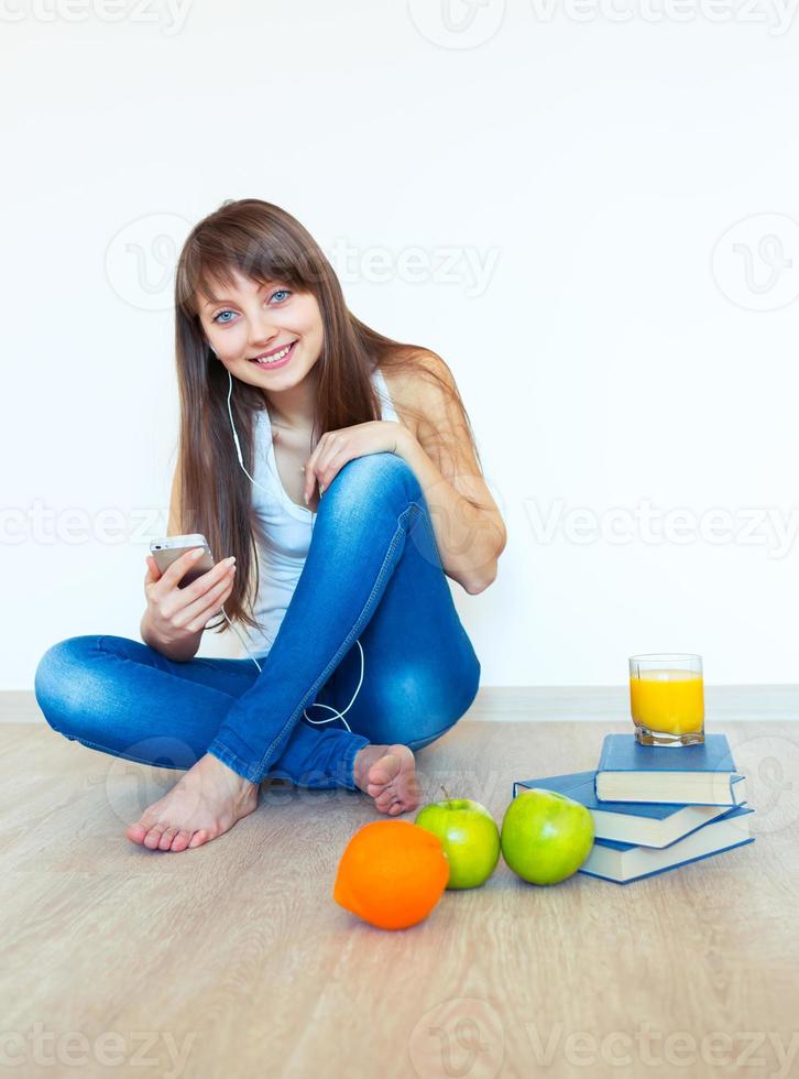 Young girl with headphones and green apple listening music at home photo