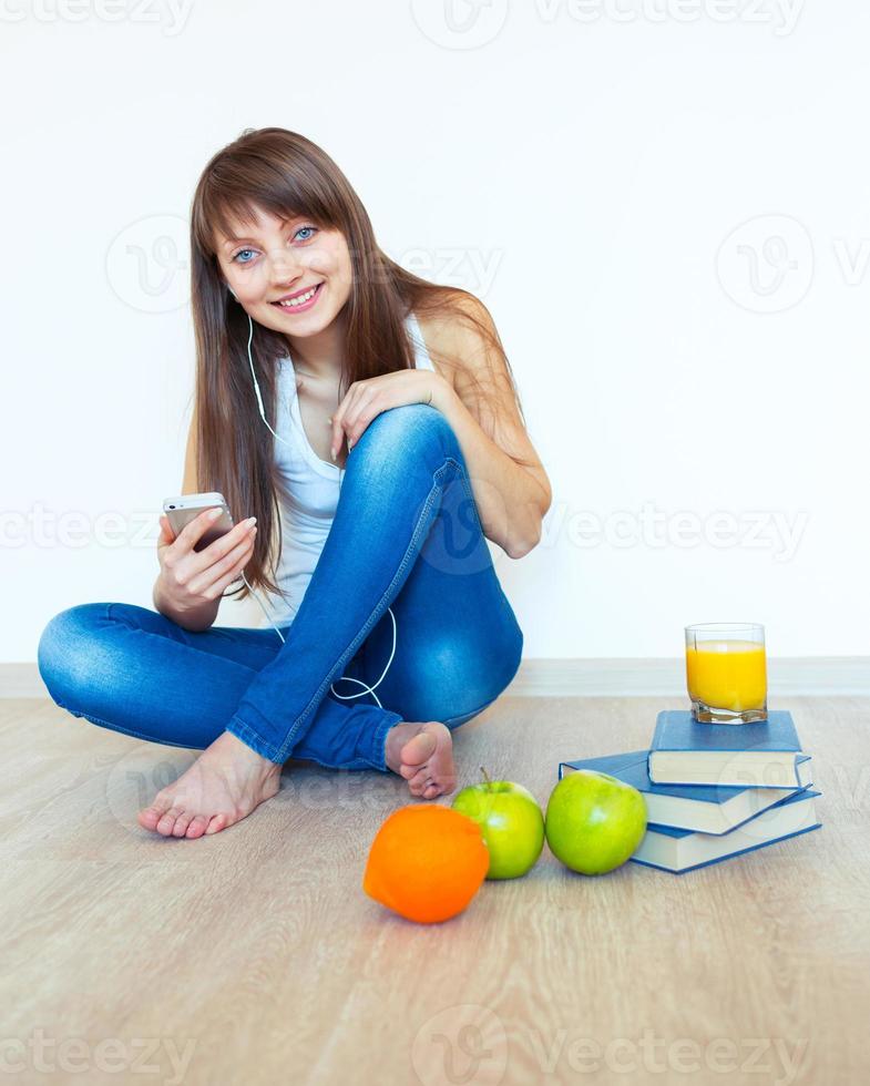 Young girl with headphones and green apple listening music at home photo