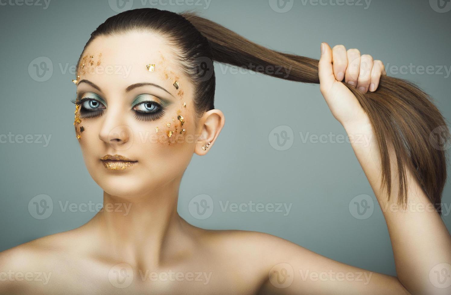 Glamorous portrait of young beautiful girl with big blue eyes, lush lashes and bright golden makeup photo