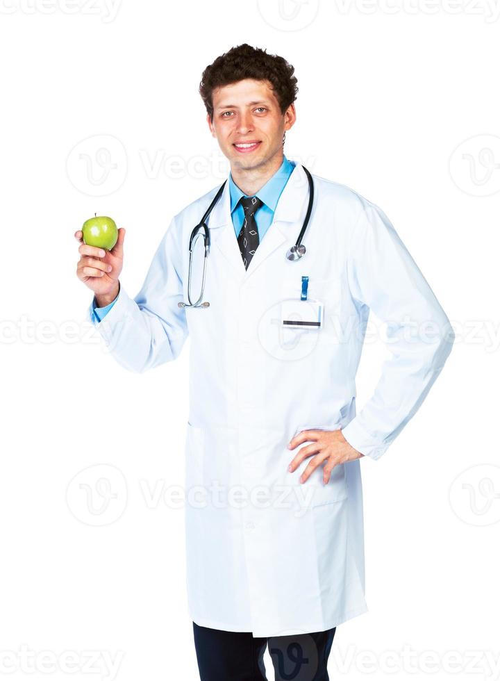 Portrait of a smiling male doctor holding green apple on white photo