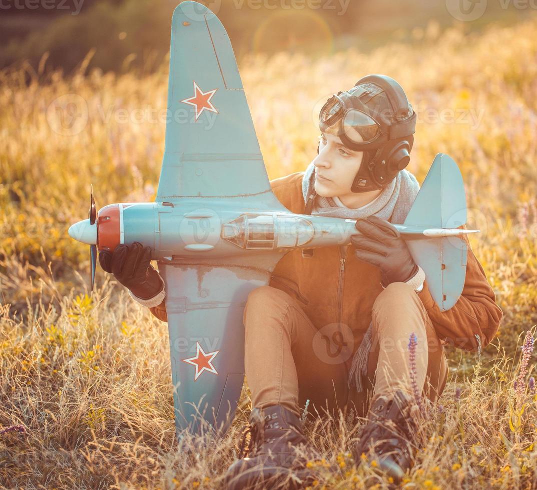 chico en Clásico ropa piloto con un avión modelo al aire libre foto