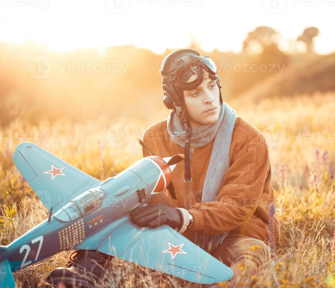 chico en Clásico ropa piloto con un avión modelo al aire libre foto