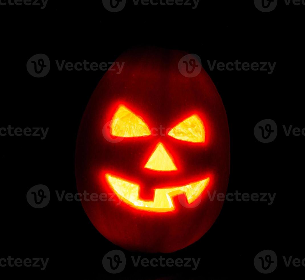 Halloween pumpkin jack-o-lantern candle lit, isolated on black photo