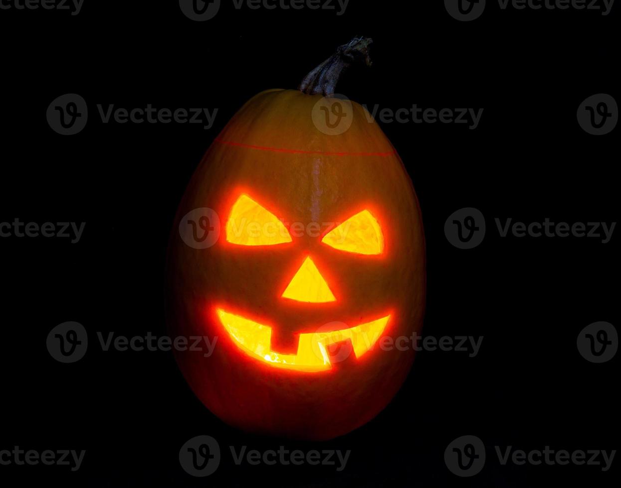 Halloween pumpkin jack-o-lantern candle lit, isolated on black photo