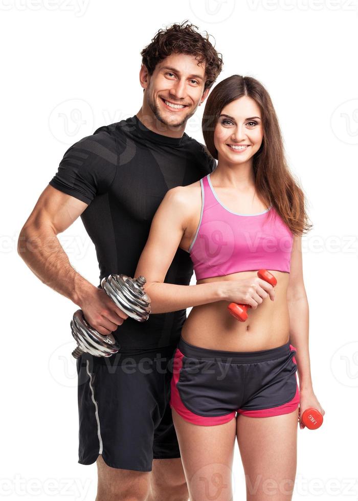 Athletic couple - man and woman with dumbbells on the white photo