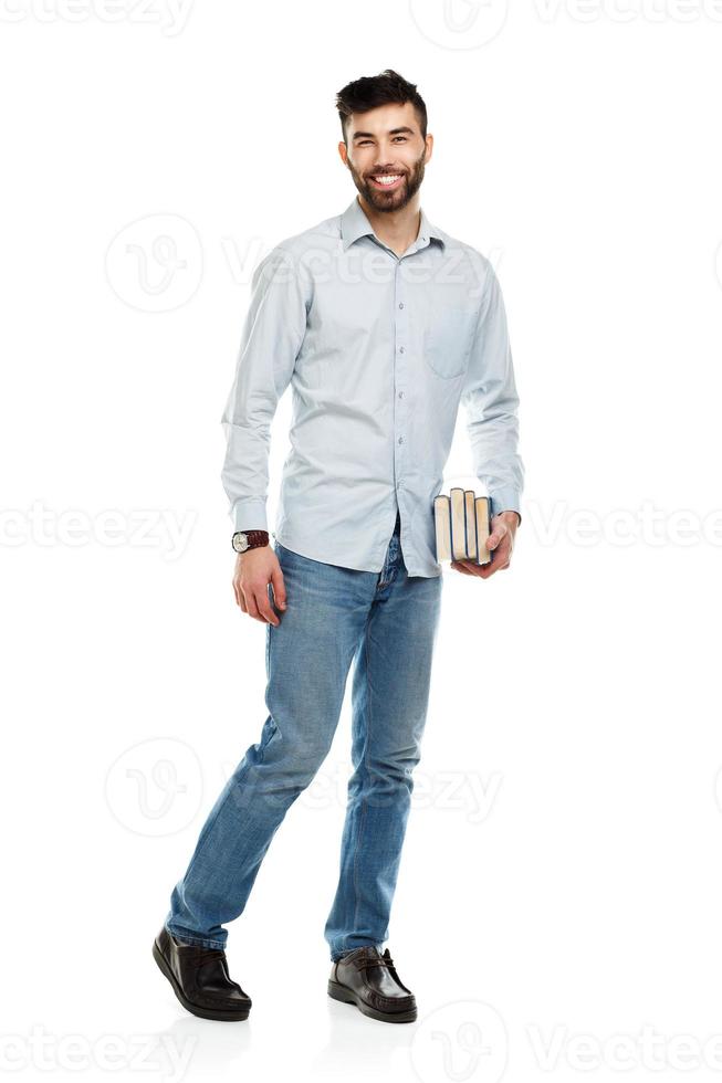 joven barbado sonriente hombre con libros en manos en blanco foto