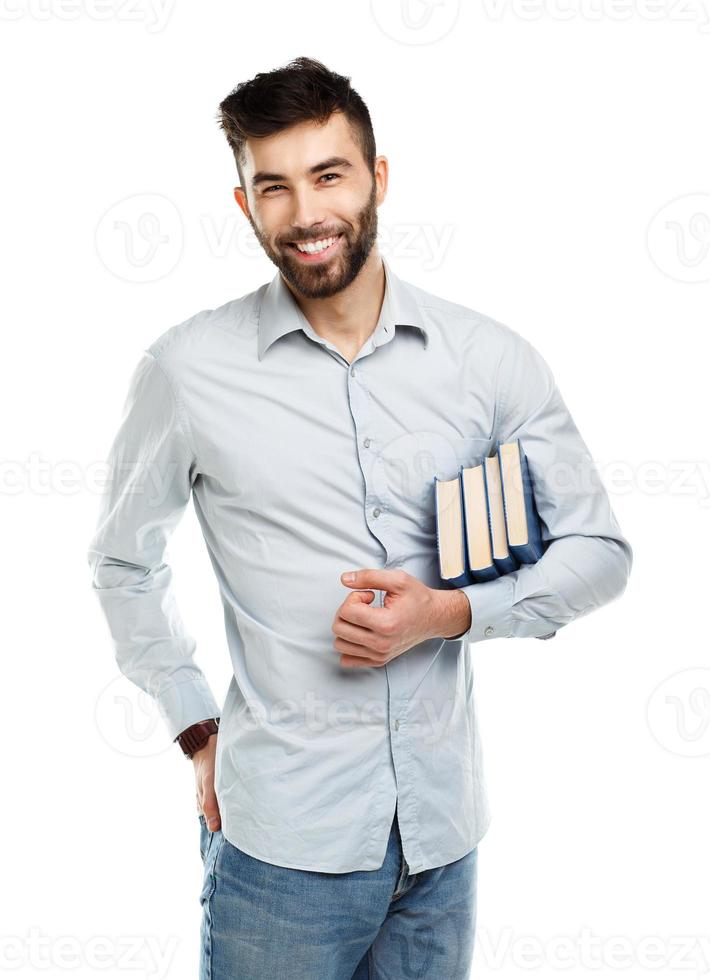 joven barbado sonriente hombre con libros en mano en blanco foto