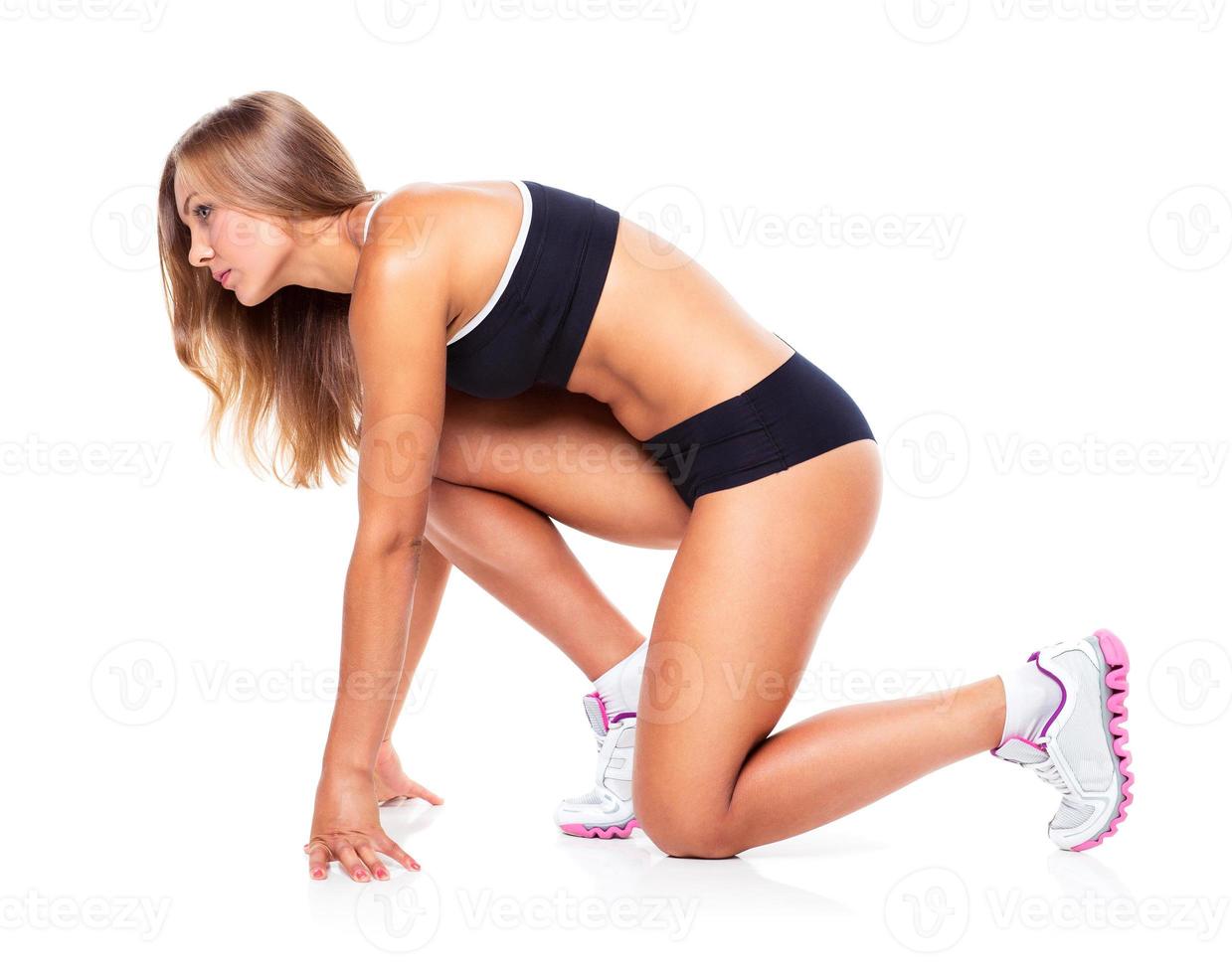 Young sports girl does exercises on a white photo