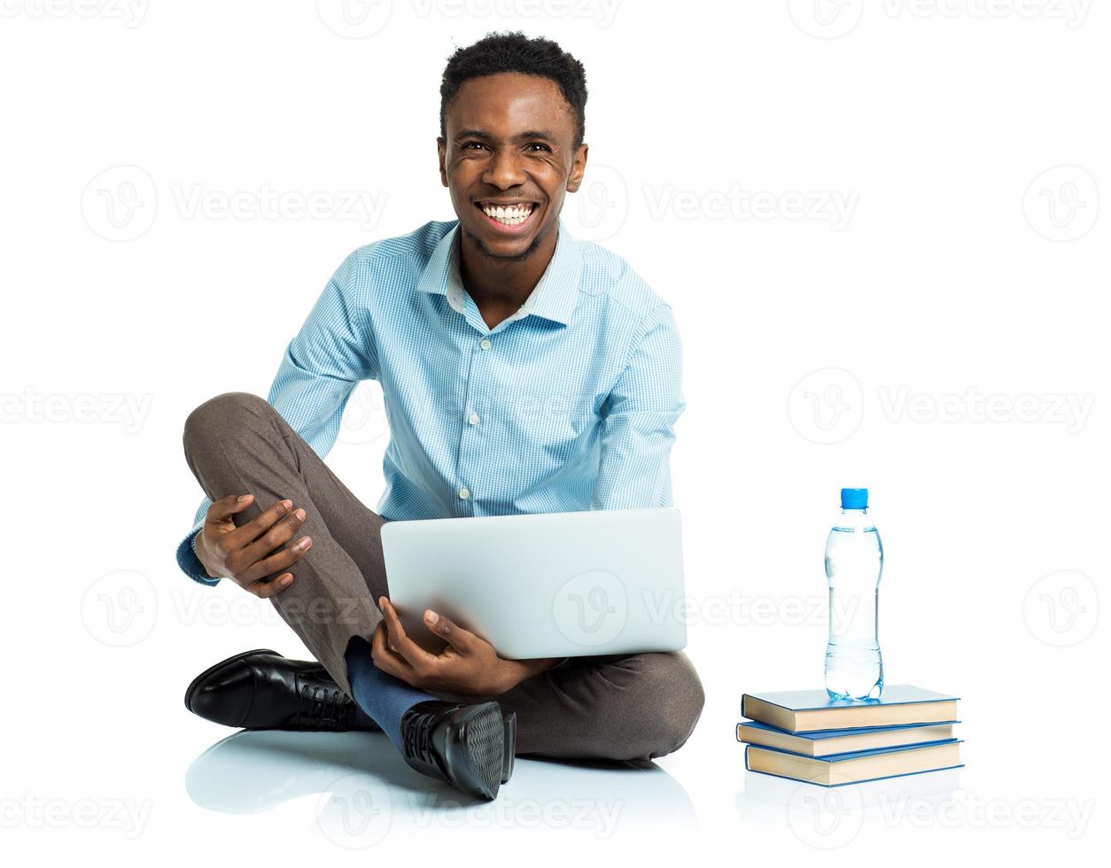 Happy african american college student sitting with laptop on white photo