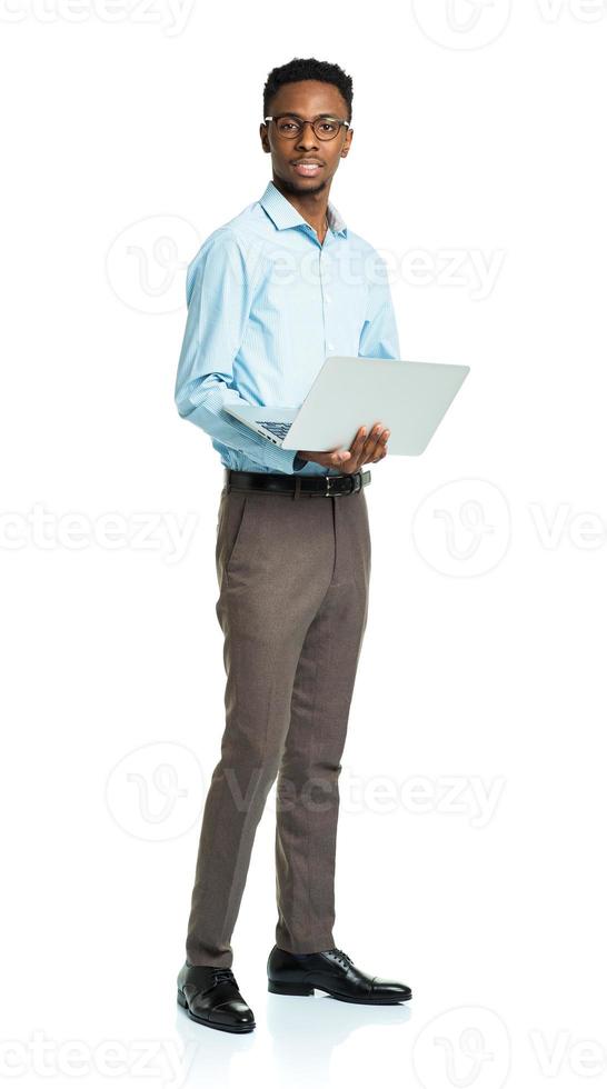 Feliz estudiante universitario afroamericano de pie con el portátil en blanco foto