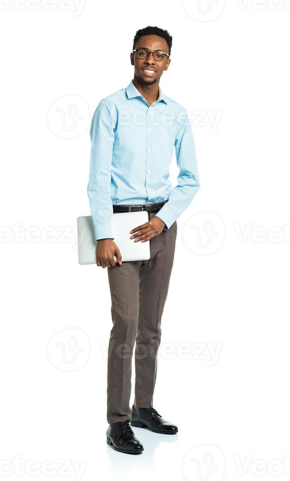 Happy african american college student standing with laptop on white photo