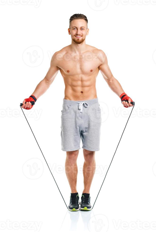 Athletic attractive man jumping on a rope on the white photo