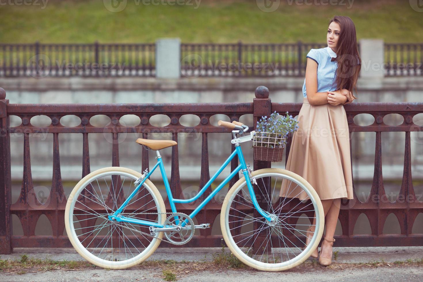 Young beautiful, elegantly dressed woman with bicycle in the park or outdoor photo