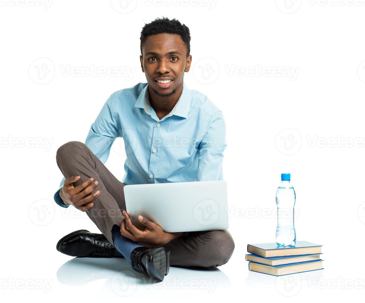 Happy african american college student sitting with laptop on white photo