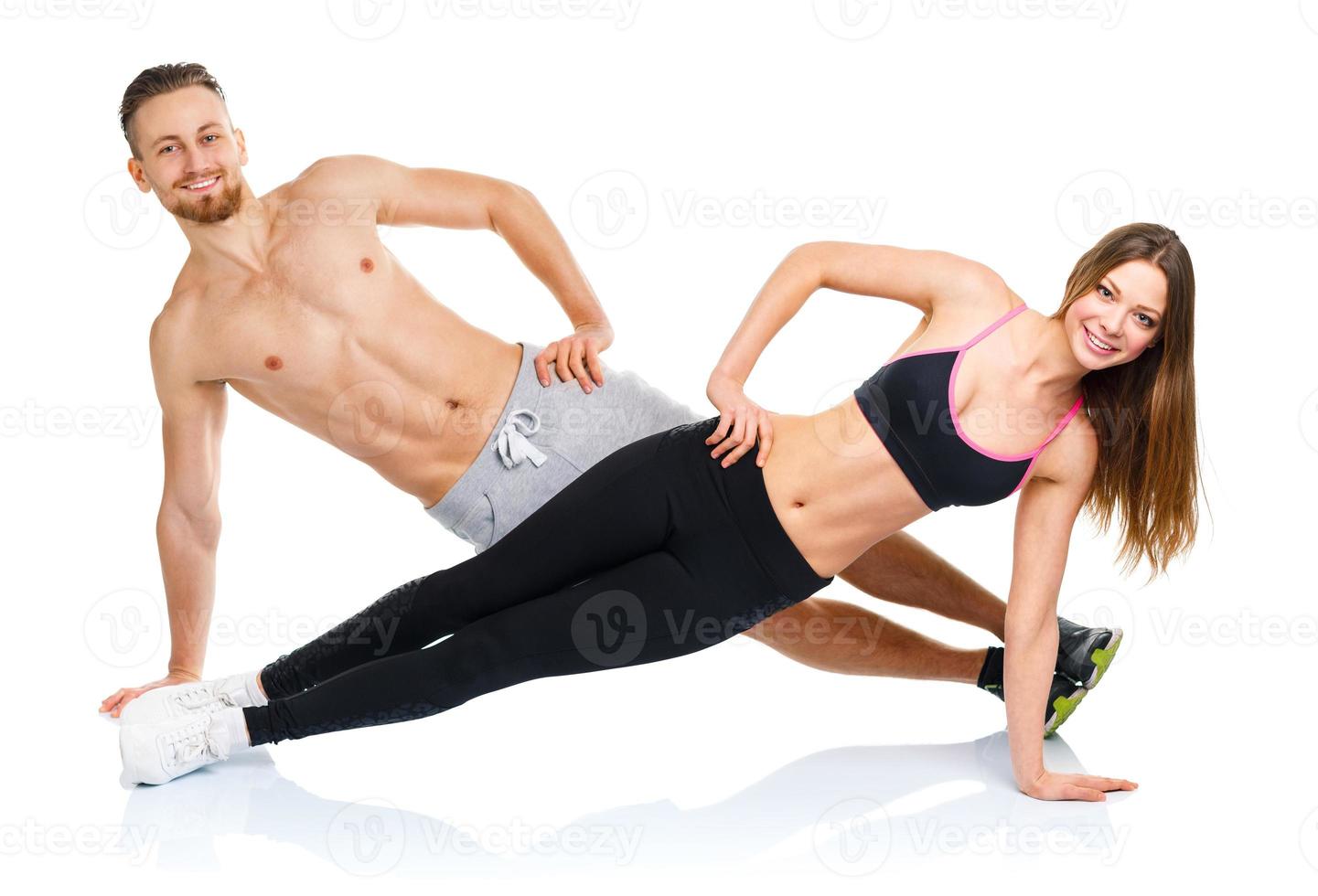 Athletic attractive couple - man and woman doing fitness exercises on the white photo