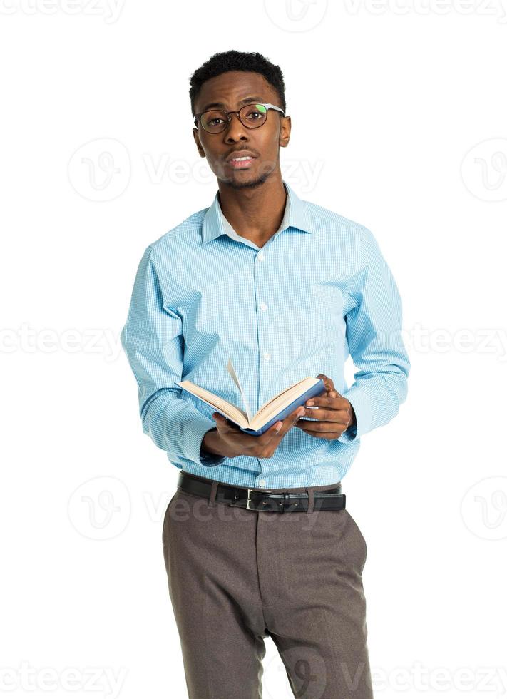 Happy african american college student standing with book in his hands on white photo