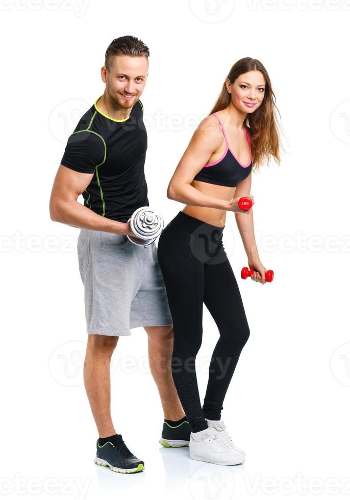 Sport couple - man and woman with dumbbells on the white photo